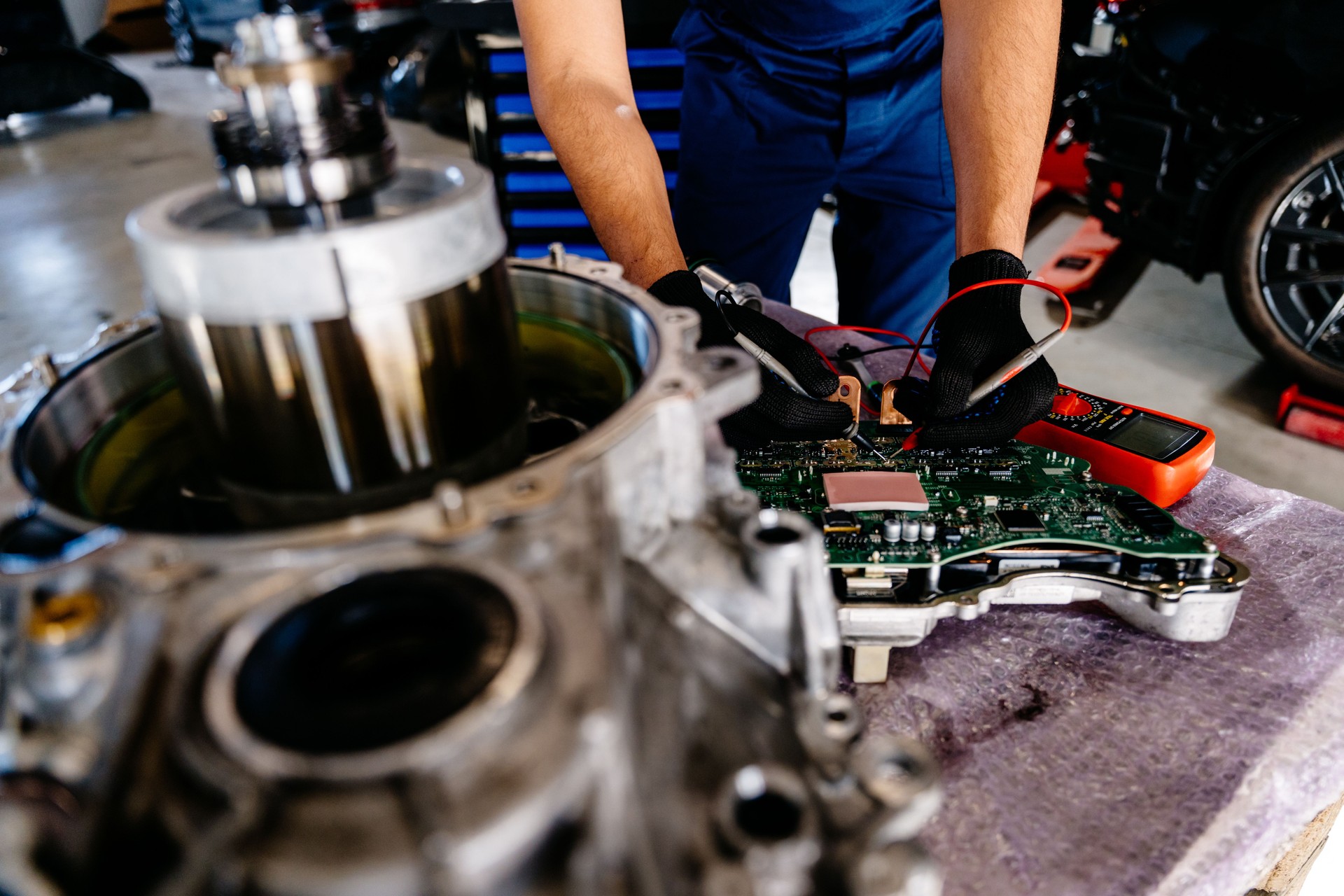 An electric car engine with a gearbox removed from a car for repair. Arabian man working Internal Permanent Magnet Synchronous Reluctance Motor. Service maintenance of industrial to engine repair.